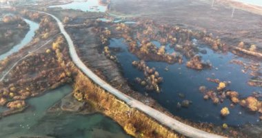 Sonbahar atmosferi etrafında yumuşak bir dere gölü arazi ve kırsal bir yol oluşturur. Ağustos 2021 'de Romanya' da çekilen en kaliteli 4K DJI Mavin 35.1 km görüntü