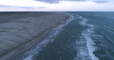 Tropikal sahil boyunca fırtına enkazı ve su dalgaları üzerinde uçuyorlar. DJI Phantom 4 PRO görüntüleri. Sahil günbatımının yansıması yerde. Eylül 2020, L epiguette, Güney Fransa 