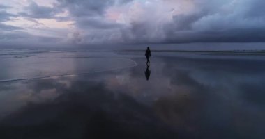 Güzel çıplak ayaklı kadın ıssız sahilde yürüyor. İnsansız hava aracı görüntüsü. DJI Phantom 4 PRO görüntüleri. Sahil günbatımının yansıması yerde. Eylül 2020, L epiguette, Güney Fransa 