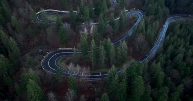 Aerial top-down drone shot above the winding mountain road close to sunset. Cars and trucks passing. High-quality DJI Mavic 3 4k 5.1k cinematic footage filmed in January 2022 in Brasov, Romania