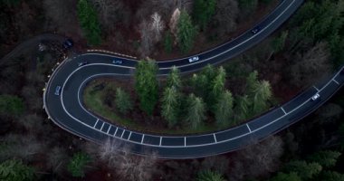 Yukardan aşağıya uçan hava aracı gün batımına yakın olan sarmal dağ yolunun üzerinde çekim yaptı. Arabalar ve kamyonlar geçiyor. Ocak 2022 'de Romanya' nın Brasov kentinde çekilen yüksek kaliteli DJI Maviç 34k 5,1 k sinematik görüntü