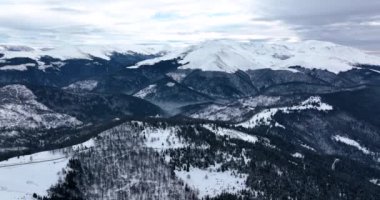 Aerial top-down cinematic winter snow-covered country road and picks. High-quality DJI Mavic 3 5.1k and 4k footage were made in January 2022 in Romania on a sunny cold day.