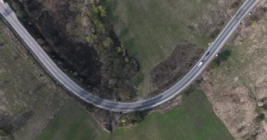 Aerial top-down cinematic summer country road Cars driving along the curved road. high-quality 5.1k DJI Mavic 3 4k footage shoot in May 2022 in South Romania