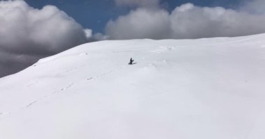 Man climbing up by snowed hill with snowboard directly above view. cinematic. High-quality DJI Mavic 3 5.1k and 4k footage made in Romania in February 2022. Beautiful winter hike. Snowy mountain.