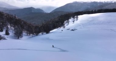 Snowboarder riding deep powder snow on a cloudy and sunny winter cold day. High-quality DJI Mavic 3 5.1k and 4k footage made in Romania in February 2022. Beautiful winter hike. Snowy mountain.
