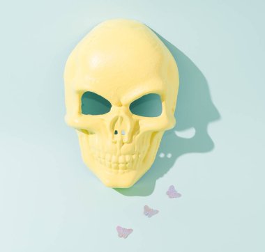 Sarı kafatası ve gölge kelebekleri izliyor. Pastel mavi arka plan. Kavramsal sanat.