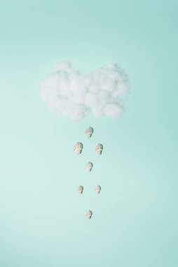 Yağmur yerine kabukların düştüğü kabarık bulutlar. Pastel arka plan. Kavramsal küme.