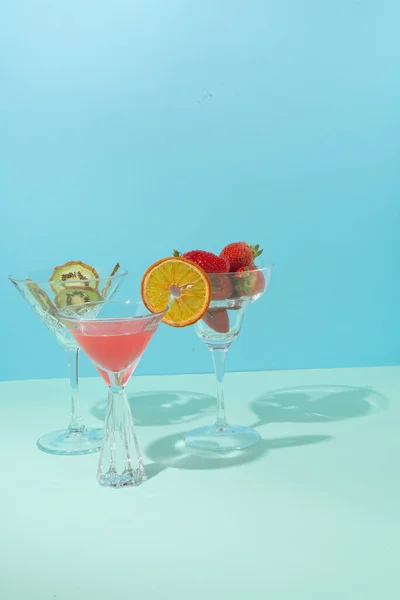 静物画の現代的な概念設定 グラスフルーツと国際色豊かなカクテルです 新鮮なイチゴとドライキウイ 背景には青の2色 — ストック写真