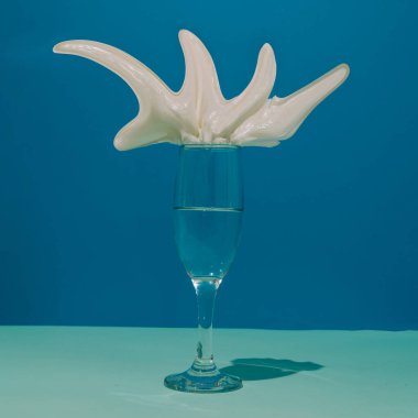 Şampanya bardağında yabani krema. İki tonlu mavi arka plan. Kavramsal küme.