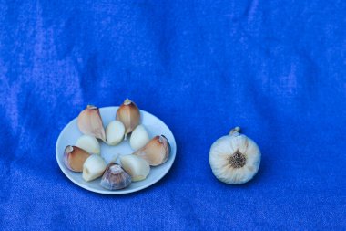 Mavi arka planda beyaz bir tabakta sarımsaklı karanfil.