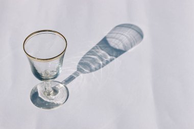 Boş bir kristal bardak ve ışık arka planında gölgesi.