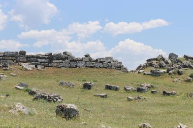 Tepedeki taş duvarın yıkıntıları Bulutlu mavi gökyüzüne karşı