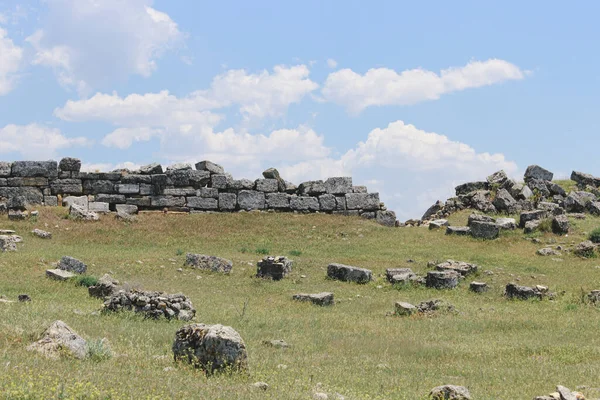 Tepedeki taş duvarın yıkıntıları Bulutlu mavi gökyüzüne karşı