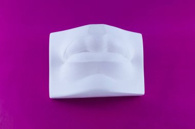 White plaster cast of lips on a purple background