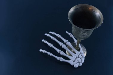 Bronze cup and skeleton hand on black background