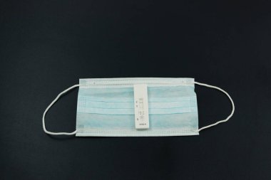 Siyah arka planda koronavirüs ve tıbbi maske testi pozitif çıktı.