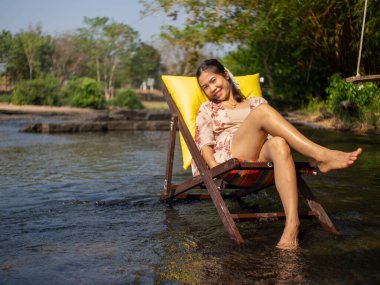 Nehrin ortasında sandalyede oturan bir kadın.