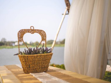 Nehrin yanındaki masada bir çiçek sepeti..