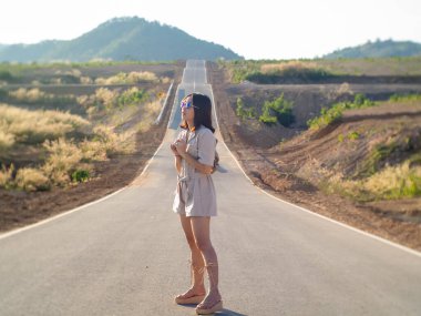 Şapkalı ve gözlüklü bir kadın yolun ortasında duruyor..