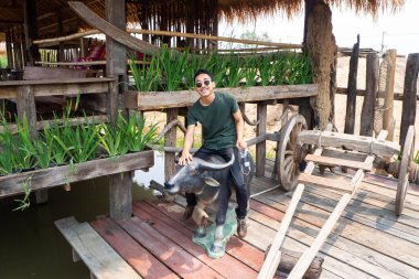 Siyah gözlüklü bir adam bufalo heykelinde oturuyor.