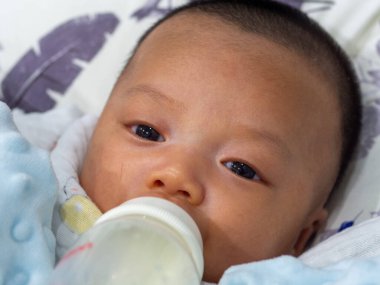 Bebek Asyalı ve Tayland uyruklu beslenme şişesinden emziriliyor.