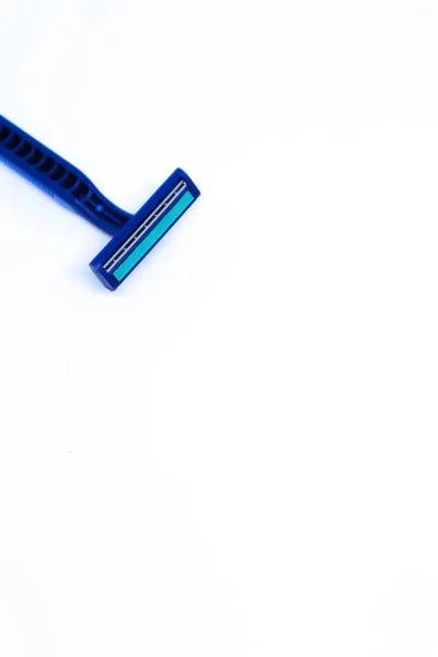 ミニマリストの白い背景の隅に青いカミソリのフラットレイショット 肖像モード — ストック写真