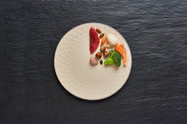 20: 4 perhiz konsepti. Sağlıklı bir tabağın üçte biri ve iki üçüncü tabak boş. Sığır eti, somon, yumurta, brokoli, domates, fındık, havuç, mantar. Karanlık arka plan. Üst görünüm.