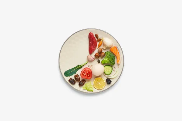 16: 8 perhiz konsepti. Sağlıklı iki üçüncü tabak ve üçüncü tabak boş. Sığır eti, somon, yumurta, brokoli, domates, fındık, havuç, mantar, salatalık, hurma. Beyaz arkaplan kopyalama alanı. Üst görünüm.