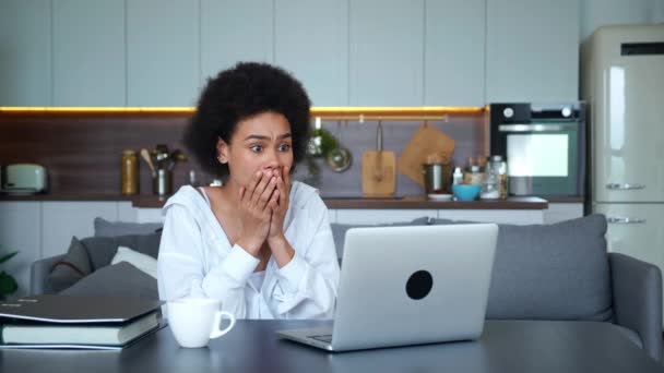 Een gefrustreerde jonge Afro-Amerikaanse vrouw kijkt met afschuw naar het beeldscherm, drukt emoties van verbijstering en afschuw uit van het slechte nieuws op de computer. — Stockvideo