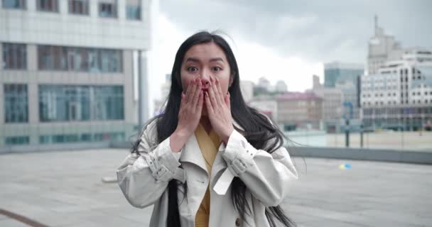 Asustado sorprendido asiático joven mujer hombre mirando cámara ver algo terrible, cubriendo la boca con las manos al aire libre en la calle de la ciudad. Gente emociones estilo de vida concepto — Vídeo de stock