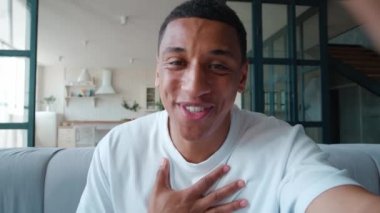 Web kamerasından ön görüntü. Yakışıklı melez adamın kollarını uzatarak akıllı telefonu tutması, web kamerasına bakması, sorgucusunu selamlaması, görüntülü konuşma yapması..