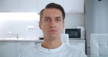 Başarıyı kutlayan, kameraya şaşıran, evdeki oturma odasındaki kanepede oturan genç adamın yakınlaşması. Zafer konsepti. Evet kazanan jest.