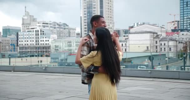 Belo casal amoroso multicultural de duas pessoas alegres dançando em data romântica no telhado de um edifício urbano. Bonito Africano cara transformando sua namorada em torno de si mesma enquanto dança — Vídeo de Stock