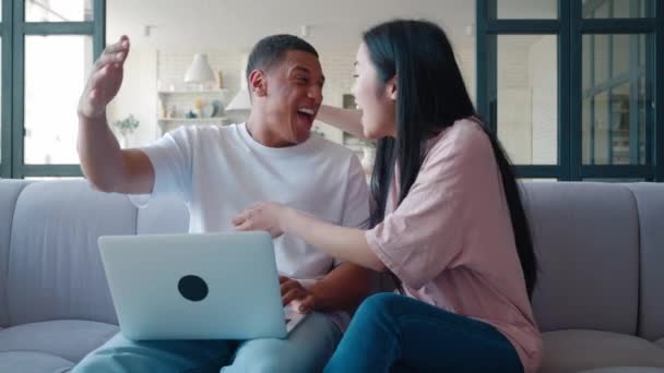 Spännande glad multiracial par tittar på skärmen av laptop känns vinnare förvånad över lotteri vadslagning vinnande bud. Härlig pojkvän och flickvän firar internet lotteri seger pris goda nyheter — Stockvideo