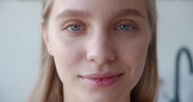 Kendine güvenen güzel sarışın bir kadının güzel yüzü. Kameraya bakıp gülümseyen dişlek bir gülümseme ve neşe içinde. Çekici kadının sabah hijyen rutininden önceki portresi..