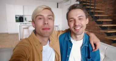 Homoseksüel çiftin video kaset çekerken sarılıp kameraya konuştuğu pov. İki gay ellerinde akıllı telefon, videolu sohbet ve evde gülümsüyor.