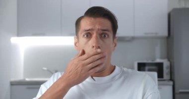 Şok olmuş ve şaşırmış bir adam evdeki kanepede oturuyor. Haberlerden korkan adam oturma odasındaki kanepede kameraya bakar..