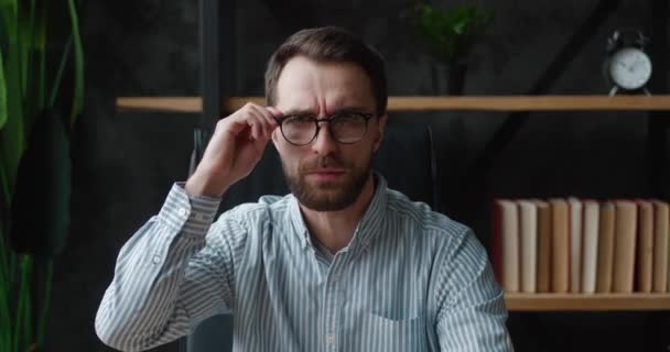 Shocked and surprised businessman sitting at office. Man in surprise shoots glasses and looks at the camera in surprise of terrible news — Stock Video