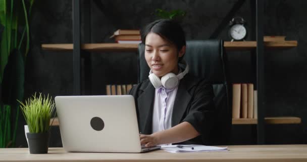 Mladá asijská obchodní žena relaxovat sedět v kanceláři stolu hotové notebook práce pocit spokojenosti s dobře odvedenou práci stresu klid mysli koncept chlad v práci. Relaxace s hudbou v kanceláři — Stock video