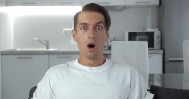 Şaşırmış erkek suratı. Şok olmuş adamın yüz ifadesini kapat. Vay be, evdeki kanepede oturan erkek duygu portresi. İyi haberlere tepki