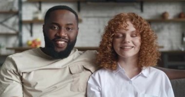 Sevimli, ırklar arası bir çiftin portresi, kucaklaşmalar, dişlek tebessümle sevimli bir gülümseme, evlerindeki mutfak arka planında poz veren kameraya bakmalar.