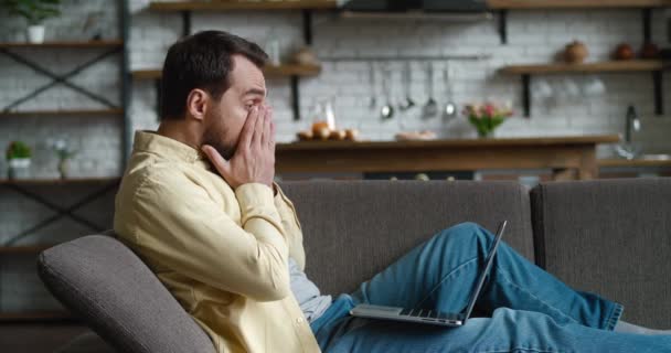 El hombre asustado está desagradablemente sorprendido y sorprendido por las malas noticias que se ven en la pantalla del ordenador portátil mientras trabaja en casa. Freelancer conmocionado sufre de estrés y desesperación — Vídeos de Stock