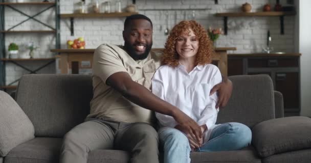 Feliz pareja interracial compartir el compromiso con un amigo en el chat de vídeo mujer mostrando anillo de boda compartir la emoción sobre la webcam, sentado en el sofá en casa. — Vídeos de Stock