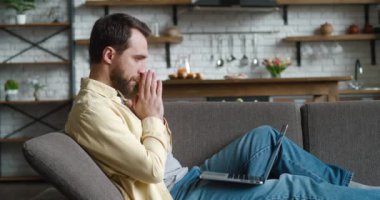 Evdeki kanepede çalışırken dizüstü bilgisayardaki kötü haberlere şaşırmış ve şok olmuş genç bir adam. Şok olmuş serbest çalışan, stres ve umutsuzluktan muzdarip.