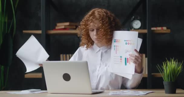 Red-haired woman with curly hair using laptop for remote video calling, takes a part in virtual meeting, showing business charts talking and discussing online, engaged in videocall, sitting at office — Stock Video