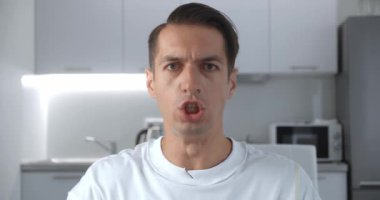 Kızgın adam, çalışanlara bağırıyor ve azarlıyor. Parmakla tehdit ediyor ve kameraya agresif bir şekilde bağırıyor. Evde oturuyor..