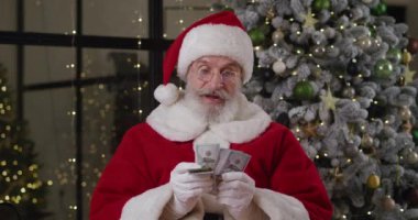 Noel Baba gibi giyinmiş mutlu yaşlı bir adam, evde hızla bir Noel ağacının arka planına karşı para sayıyor, para faturalarını kendine sıkı sıkı tutmaktan zevk alıyor. Yeni yıl ve Noel konsepti