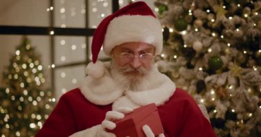 Noel Baba sihirli parlayan hediye kutusunu açar ve içine bakar, kutudan parlak bir ışık parlar. Mutlu yıllar ve Noel.