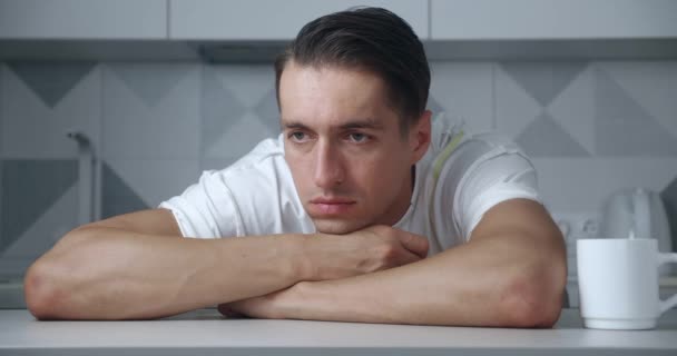 Evdeki masada oturan endişeli ve stresli genç adamın portresi. Depresyondaki erkek keder ya da başarısızlıktan muzdarip — Stok video