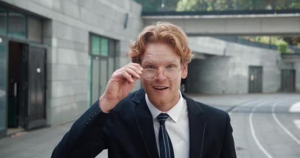 Amazed shocked redheaded business man in classical suit takes off his glasses and looks at the camera in surprise. Smiling stylish male in formal suit happy by great news — Stock Video